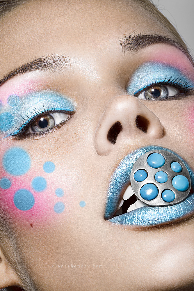 Girl covered with a blue make-up holds ring in her mouth | make-up, ring, mouth